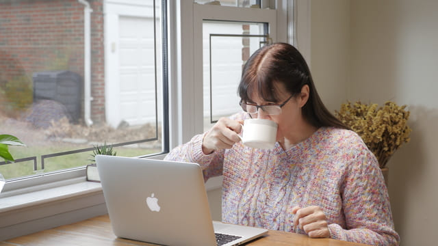 una cristiana guarda il computer bevendo un caffè